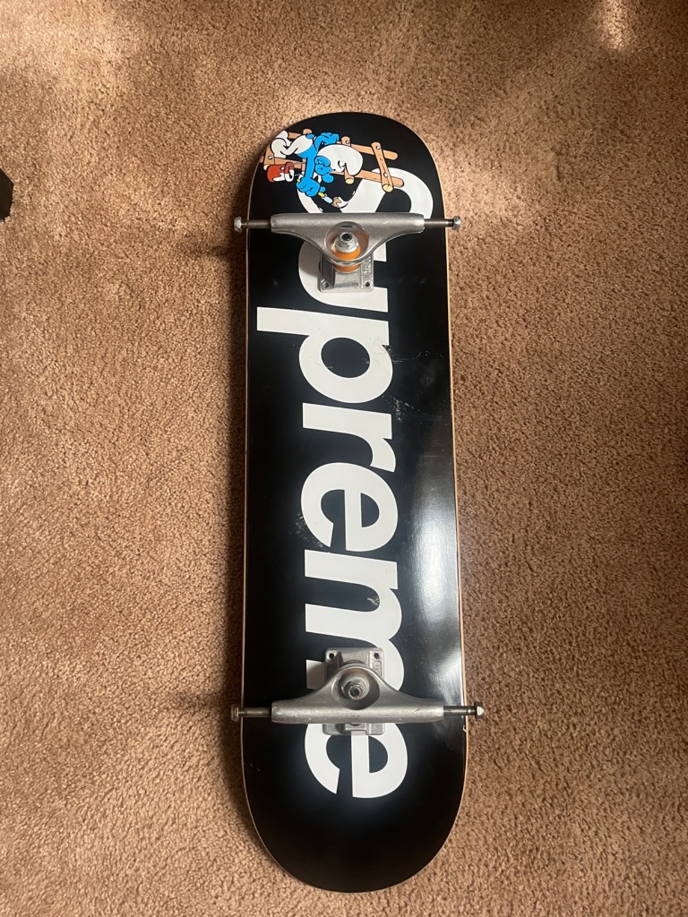 Supreme Black Skateboard Deck with White Logo and Colorful Character